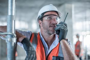 Mid adult male site manager using walkie talkie on construction site